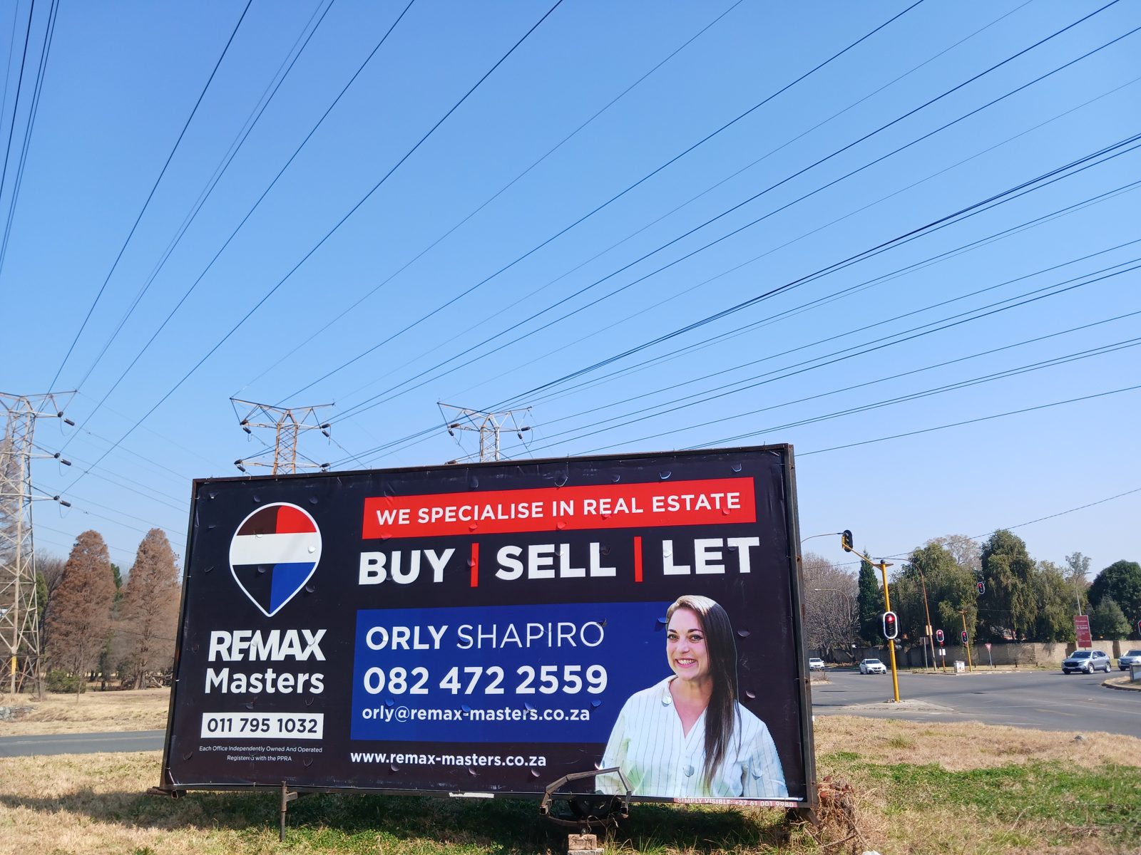 RE/MAX Masters agent billboard on a Simply Visible trailer at a traffic-light intersection