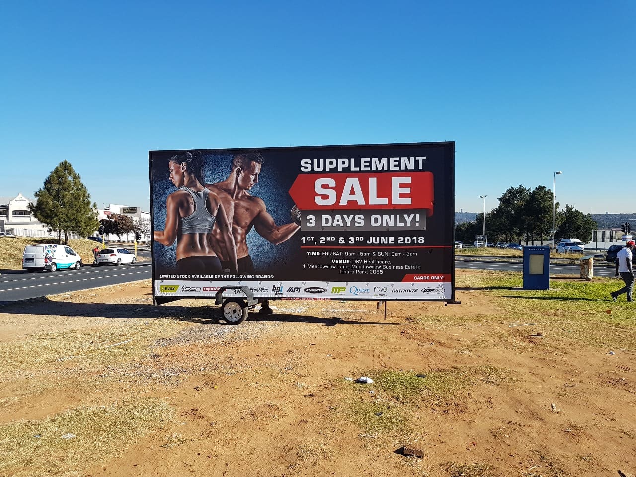 A Simply Visible billboard trailer parked on the verge of a busy Gauteng road, carrying a large printed advert facing the traffic
